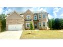Charming brick home with a two-car garage, green lawn, and blue skies at 306 Rodeo Dr, Auburn, GA 30102