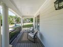 Relaxing covered porch featuring comfortable seating, classic columns, and a view of the serene neighborhood at 6084 Queens River Dr, Mableton, GA 30126