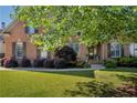 Charming brick home featuring a lush green lawn, mature trees, and manicured landscaping at 3641 Carriage Glen Way, Dacula, GA 30019
