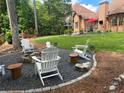 Backyard features a seating area with white Adirondack chairs and a grassy area for outdoor activities at 6510 Newcastle Way, Cumming, GA 30040