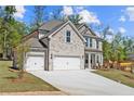 Beautiful stone fronted home with a wide driveway and three car garage, surrounded by lush trees at 6944 Melody Ridge Rd, Buford, GA 30518