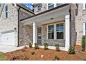 Inviting front porch with stone accents, manicured shrubs, and view of a three car garage at 6944 Melody Ridge Rd, Buford, GA 30518