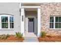 A covered front porch with a gray door and white columns gives this home an inviting entrance at 4810 Floydwood Ln, Mableton, GA 30126