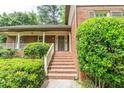 Home featuring a brick stairway and covered porch with a wooden railing leading to the front door at 7310 Ne Wynhill Ne Dr, Atlanta, GA 30328