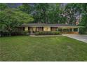Charming brick home with a well-manicured lawn, mature trees, and covered parking at 4807 Kenilworth Dr, Stone Mountain, GA 30083