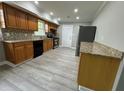 Functional kitchen with wood cabinets, stone countertops, mosaic backsplash, and gray wood-look flooring at 3078 Michael Sw Dr, Marietta, GA 30060
