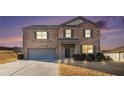 Charming two-story brick home with a gray garage door and landscaped front yard at dusk at 8484 Glenview St, Douglasville, GA 30134