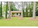 Single-story house featuring a front porch and surrounded by mature trees and a lush green lawn at 2621 Manor Pl, Ellenwood, GA 30294
