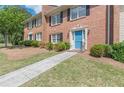 Brick townhome showcasing a blue front door, trimmed bushes, and a concrete walkway at 4101 Dunwoody Club Dr # 49, Atlanta, GA 30350