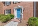Close-up of a brick townhome entrance with a blue door and manicured landscaping at 4101 Dunwoody Club Dr # 49, Atlanta, GA 30350