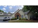 Inviting home with attached garage, brick entryway, manicured lawn and lush landscaping at 1231 Creek Forest Ln, Austell, GA 30106