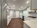 Modern kitchen featuring stainless steel appliances, white cabinets, quartz countertops, and hardwood floors at 1341 Beeblossom Trl, Lawrenceville, GA 30044