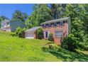Two-story brick home with a two-car garage, lush green lawn, and mature trees at 1076 Plantation Se Blvd, Conyers, GA 30094