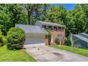 Brick home with an attached garage, mature trees, and a well-maintained front lawn at 1076 Plantation Se Blvd, Conyers, GA 30094