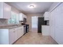 Functional kitchen featuring white cabinets, stainless steel appliances, and neutral tile flooring at 1076 Plantation Se Blvd, Conyers, GA 30094