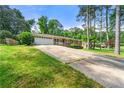 View of home from driveway with a well-manicured lawn, tall trees, and attached garage at 4590 Sims Ct, Tucker, GA 30084