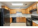 This kitchen features oak cabinets, a black gas range, a black dishwasher, and a double-basin sink at 3531 Brookstone Way, Union City, GA 30291