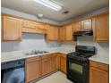 This kitchen features oak cabinets, a black gas range, a black dishwasher, and a double-basin sink at 3531 Brookstone Way, Union City, GA 30291