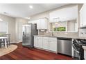Well-lit kitchen featuring stainless steel appliances, white cabinets, granite countertops, and hardwood floors at 5010 Foxberry Ln, Roswell, GA 30075