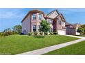 Brick home showcasing lush green lawn, partial view of siding and a driveway leading to a two-car garage at 205 Kestrel Cir, Covington, GA 30014