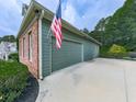 Attached garage with gray door, siding, brick accents, and American flag at 302 Gilmer Ct, Canton, GA 30115