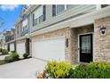 Inviting townhome showcasing a two-car garage, partial stone facade, manicured landscaping, and front door at 2140 Ravencliff Dr, Austell, GA 30168