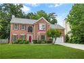 Inviting brick home with red shutters, showcasing a manicured front yard and an attached two-car garage at 5070 Saddle Bridge Ln, Alpharetta, GA 30022