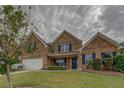 Charming two-story brick home with landscaped front yard, dark shutters and a two car garage on an overcast day at 4952 Terrace Dr, Ellenwood, GA 30294