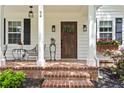 Inviting front porch with brick flooring, seating, plants, and decorative exterior lighting fixtures at 94 Glenn Se St, Atlanta, GA 30312
