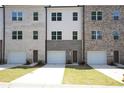 A row of newly constructed townhomes each featuring individual one-car garages and unique brick designs at 4962 Villager Ln, Stone Mountain, GA 30083