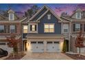 Exterior of a two-story townhouse with a two-car garage and blue and brick accents at dusk at 305 Duval Dr, Alpharetta, GA 30009