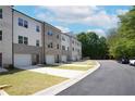 A row of townhomes with brick and siding, each featuring a single car garage and grassy front lawns at 4960 Villager Ln, Stone Mountain, GA 30083