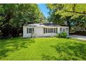 A charming one-story home with green shutters and lush green lawn, surrounded by mature trees at 4742 West Dr, Forest Park, GA 30297