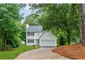 Beautiful two-story home surrounded by lush green trees, featuring a brick pathway and an attached garage at 2040 Sunrise Cir, Cumming, GA 30040