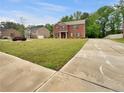 Charming two-story brick home with a lush green lawn and long driveway in a quiet, residential neighborhood at 1477 Harlequin Way, Stockbridge, GA 30281