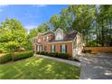 Two-story brick home with attached garage, mature trees, and a well-maintained lawn on a sunny day at 5661 Fairwood Nw Dr, Acworth, GA 30101