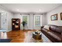 Cozy living room features hardwood floors, a leather sofa, and lots of natural light from the large windows at 5661 Fairwood Nw Dr, Acworth, GA 30101