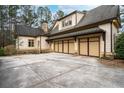 Side view of a three-car garage with attached home featuring stone accents and manicured landscaping at 6213 Arnall Nw Ct, Acworth, GA 30101
