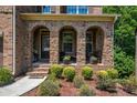 Arched brick front porch with potted plants and cozy seating area, surrounded by manicured landscaping at 1185 Gallatin Way, Suwanee, GA 30024