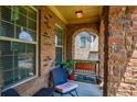 Covered front porch area featuring brick walls and a seating area with windows at 1185 Gallatin Way, Suwanee, GA 30024