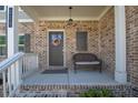 Inviting porch with brick accents, a cozy bench, and a decorated front door at 211 Aspen Valley Ln, Dallas, GA 30157
