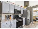 A modern kitchen with stainless steel appliances, granite countertops, and light gray cabinets at 995 Chimney Trace Way, Lawrenceville, GA 30045