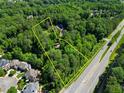Expansive wooded property with a long road front and outlined lot boundaries from an aerial view at 605 Ga 120 Hwy, Roswell, GA 30075