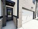 Inviting townhome entrance with attached garage, brick accents, and modern black door at 5702 Urban Village Way # 2, Tucker, GA 30084