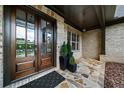 Inviting front porch with stone flooring, a wooden front door with glass panes, and potted plants at 885 Old Peachtree Ne Rd, Lawrenceville, GA 30043