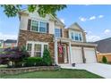 Charming two-story home showcasing a stone facade, a two-car garage, and manicured landscaping at 971 Reap Lane, Lawrenceville, GA 30043