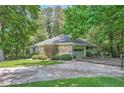 Residential home featuring a driveway leading to a garage, surrounded by a stone facade, greenery, and tall trees at 125 Fortuna Ct, Roswell, GA 30075
