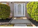 Close-up of a white front door, adorned with glass detailing and flanked by meticulously trimmed bushes at 6252 Selborn Sw Dr, Atlanta, GA 30331