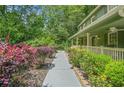 A sidewalk leads to a covered front porch and features a well-maintained landscape with flowers, shrubs, and lush foliage at 220 Hillswick Ct, Atlanta, GA 30328