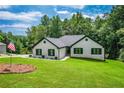 Beautiful white brick home with a well-kept lawn, surrounded by lush trees and an American flag at 2334 Fisher Dr, Loganville, GA 30052